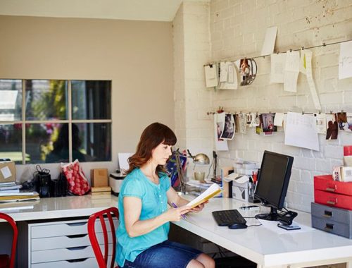 Femme en télétravail devant son cahier et son ordinateur à côté d'une Imprimante multifonction Xerox C315.