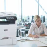To kvinder arbejder på et kontor ved siden af en Xerox® VersaLink® C625-multifunktionsfarveprinter
