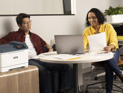 To personer på kontoret ved siden af Xerox® C410-farveprinteren