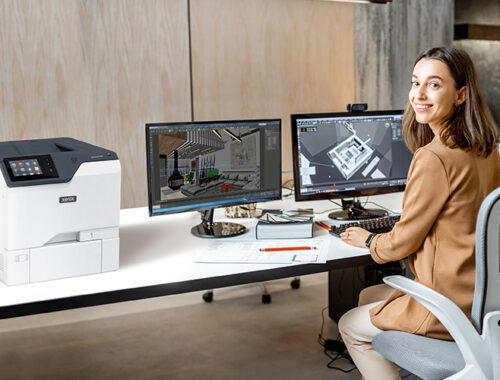 Mulher em um escritório ao lado da impressora Xerox® VersaLink® C620