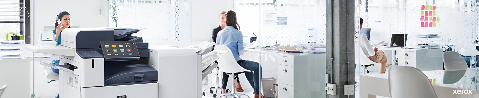 Um escritório espaçoso com uma impressora Xerox® e um computador sobre uma secretária, proporcionando um ambiente de trabalho profissional.