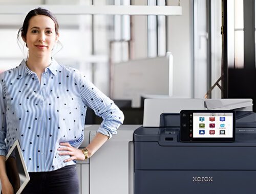 Uma mulher em pé ao lado da impressora Xerox® PrimeLink® Série C9200 em um ambiente de escritório moderno