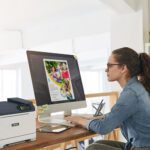 A woman seated at a desk, focused on her work, with a Xerox® C320 Colour Printer