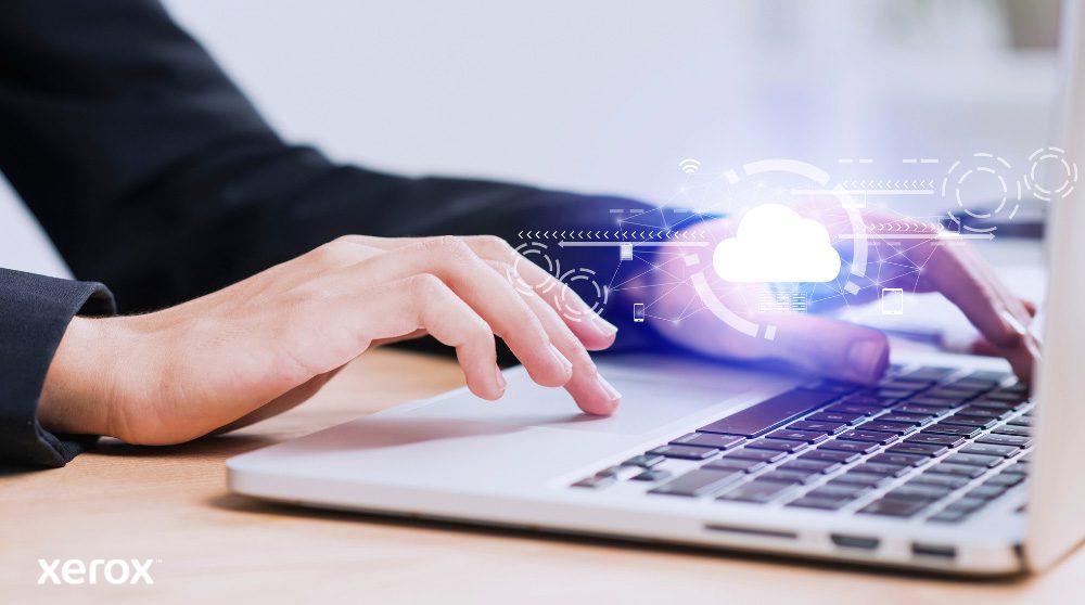 Er worden iemands handen getoond die op een laptoptoetsenbord typen, met een gloeiend wolkpictogram en netwerkverbindingen over de afbeelding heen, wat symbool staat voor cloudconnectiviteit en digitale workflows.